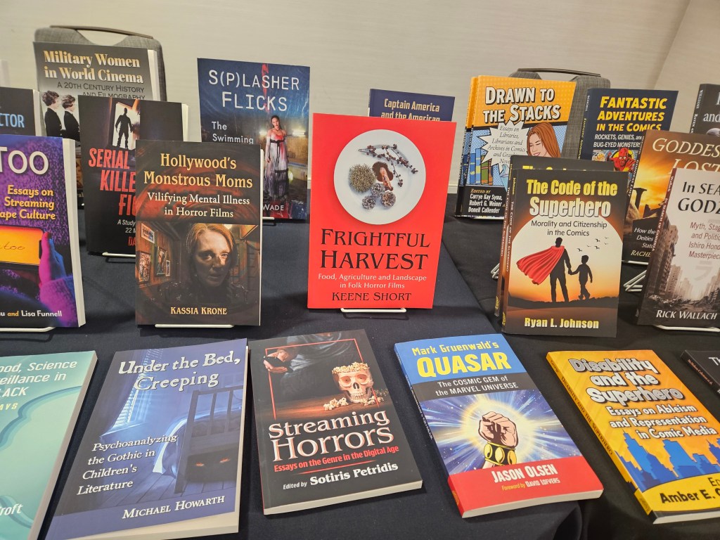 A copy of Frightful Harvest: Food, Agriculture, and Landscape in Folk Horror Films by Keene Short, next to several other pop culture studies books on display on a table. 