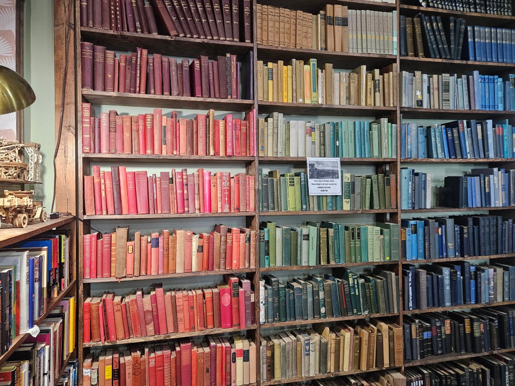 Bookshelf with books arranged by color, red on the right and green and blue on the left.